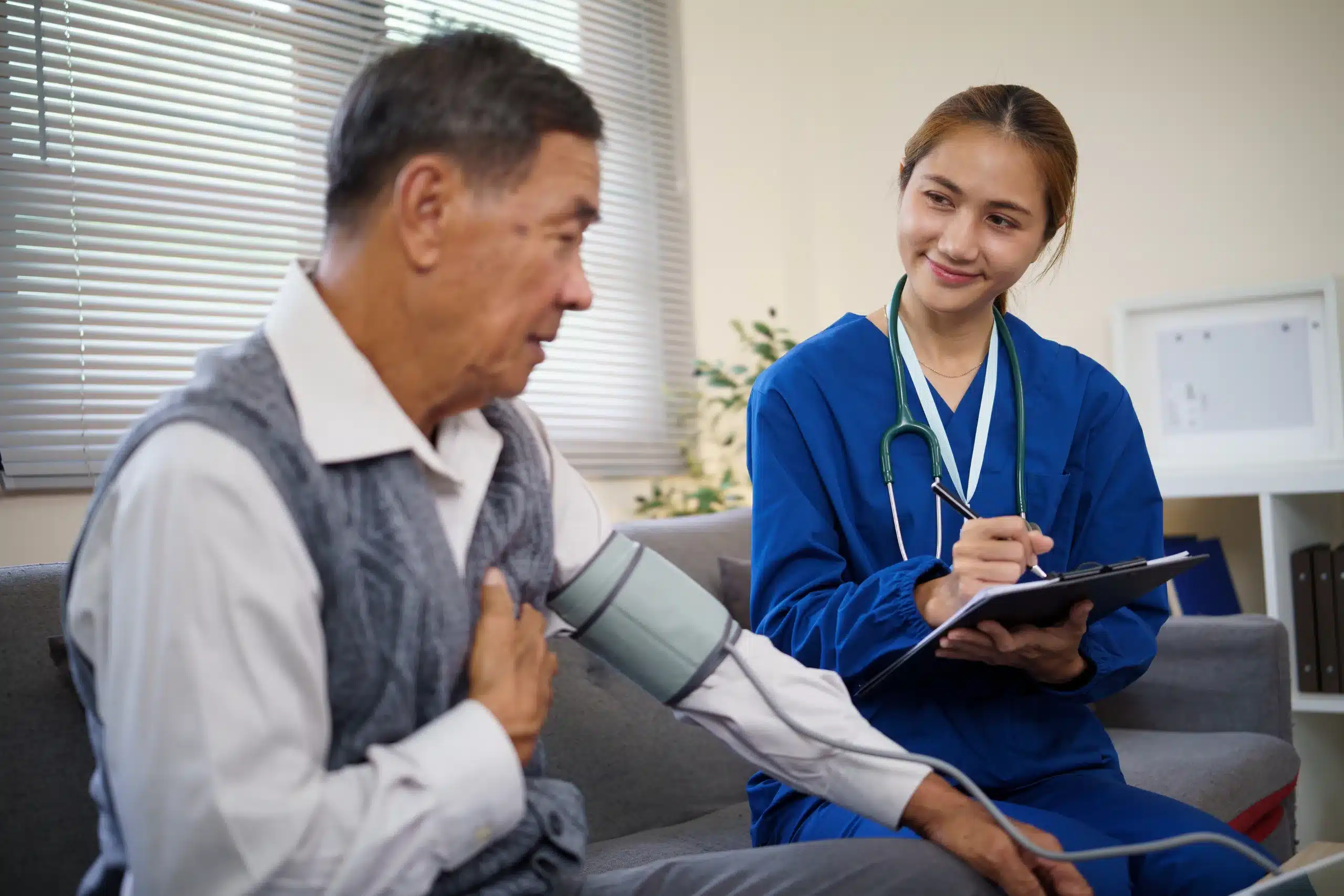 A nurse measures the blood pressure of an elderly man in a clinical setting, ensuring his health and well-being.